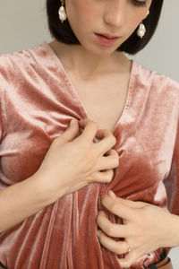 Midsection of thoughtful woman standing against gray background