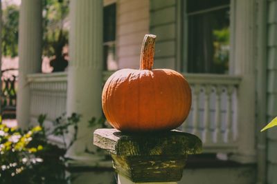 One pumpkin standing alone in front of house.