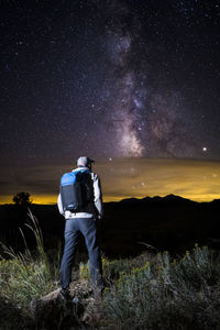 Rear view of man standing on field at night