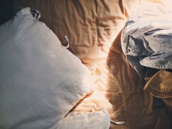 Directly above shot of pillow by crumpled sheet on bed