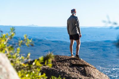 Rear view of man standing on rock by sea