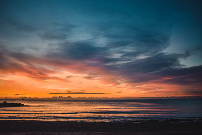 Scenic view of sea against dramatic sky during sunset