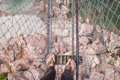 Low section of man standing on chainlink fence