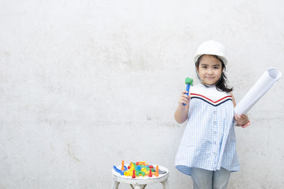 Portrait of smiling girl standing against wall