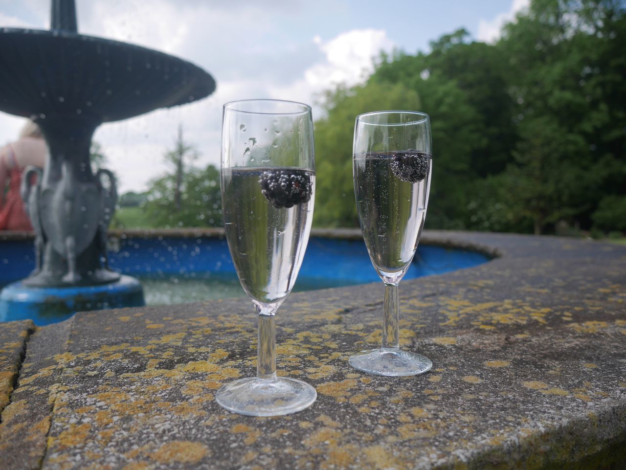 water, refreshment, focus on foreground, drinking glass, close-up, transparent, wineglass, freshness, drink, food and drink, splashing, glass - material, reflection, bubble, motion, day, drop, fountain, nature, sky
