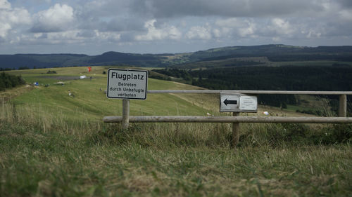 Information sign on field against sky