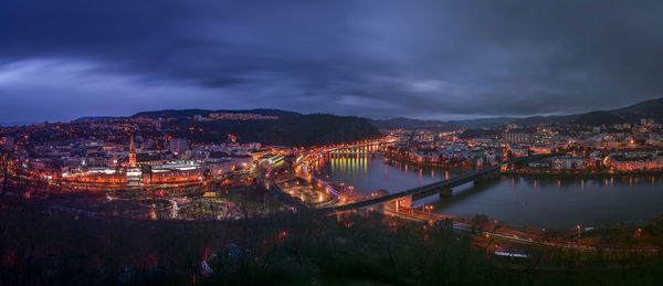 High angle view of illuminated buildings by river against sky at night