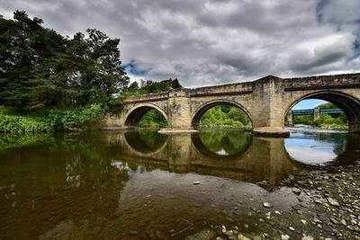 Arch bridge over river against sky