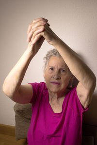 Portrait of woman with hands clasped against wall at home