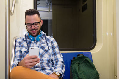 Young man using phone while traveling in train