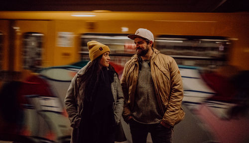 Couple standing by train at railroad station