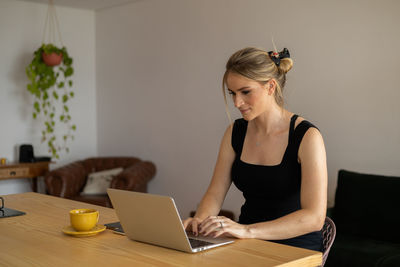 Side view of young man using laptop at home