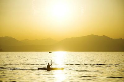 Silhouette man sailing in against sky during sunset