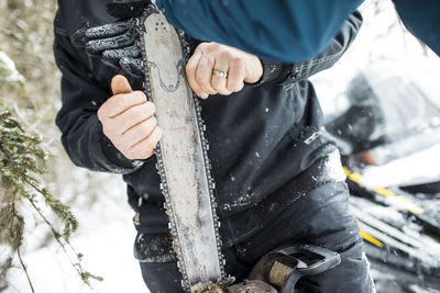 Arborist fixing chain on chainsaw outdoors.