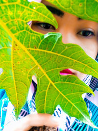 Close-up portrait of boy with green leaf