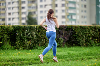 Rear view of woman with arms raised on field