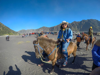 Woman horseback riding at desert during sunny day