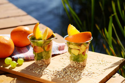 Fruits in disposable cups on cutting board over table