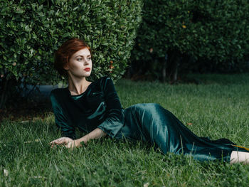 Young woman looking away while lying on lawn