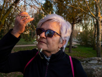 Close-up of senior woman smelling cherry blossoms