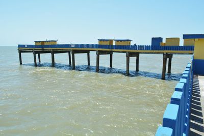Pier over sea against clear blue sky