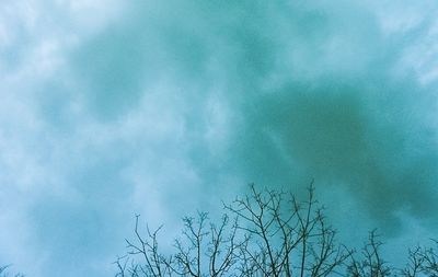 Low angle view of bare tree against cloudy sky