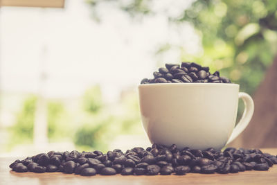 Close-up of coffee beans with cup on table