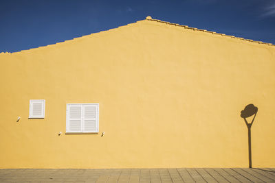 Low angle view of yellow house against sky