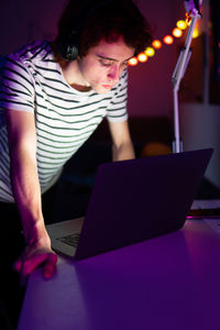 Man using laptop while sitting in darkroom