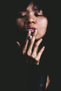 Close-up of woman smoking cigarette in dark