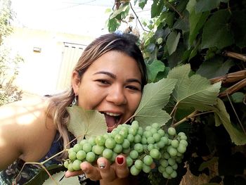 Portrait of happy woman with fruits on plant