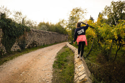 Rear view of woman walking on road amidst trees