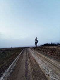 Road amidst field against sky