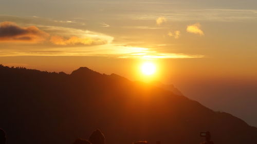 Scenic view of silhouette mountains against orange sky