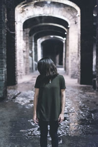 Woman standing at passage of abandoned building