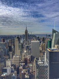 Modern buildings in city against cloudy sky