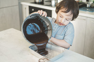 Boy pouring batter in baking tin