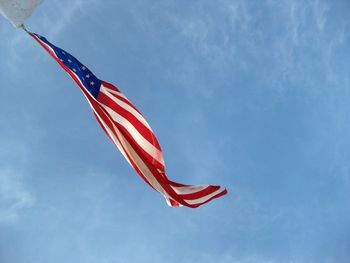 Low angle view of american flag against blue sky