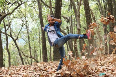Man kicking dry leaves in forest