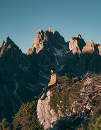 Man on rock by mountains against sky