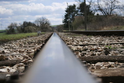 Surface level of railroad track amidst trees against sky