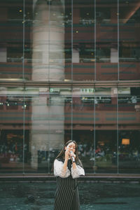 Full length of man photographing with mobile phone while standing outdoors
