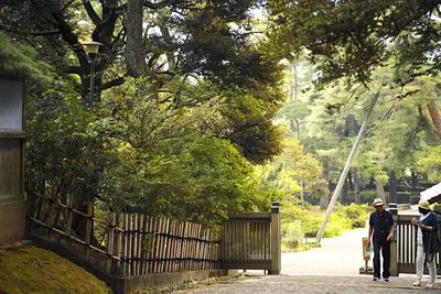 Man standing by railing against trees