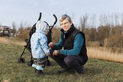 Portrait of mature man with baby girl relaxing at field