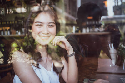 Portrait of smiling woman in cafe seen through glass window