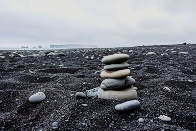 Stack of pebbles on beach against sky