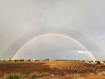 Scenic view of rainbow over field against sky