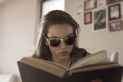 Woman wearing sunglasses while reading book