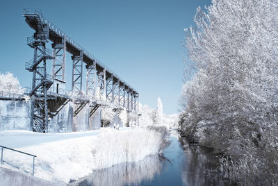 Bridge over river against clear sky during winter