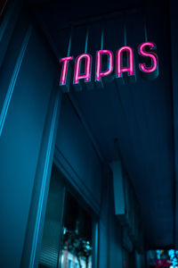 From below pink tapas sign hanging outside diner in evening on town street